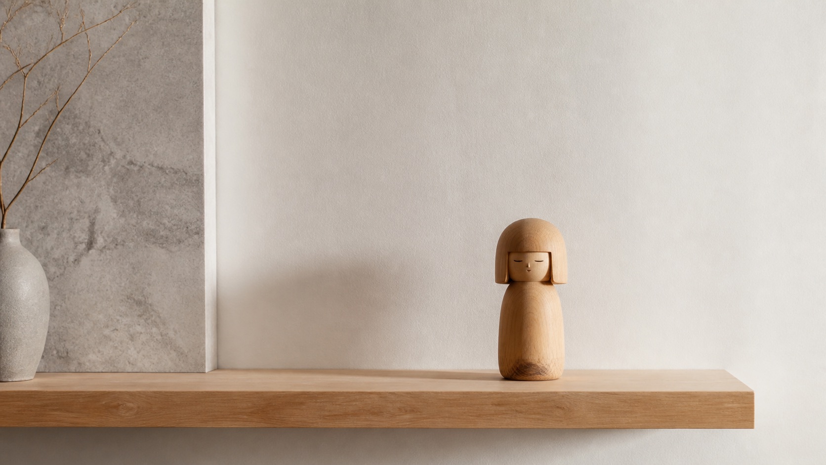 Japansk figur — en minimalistisk kokeshi-trädocka på en hylla med tomrum i ett dämpat rum